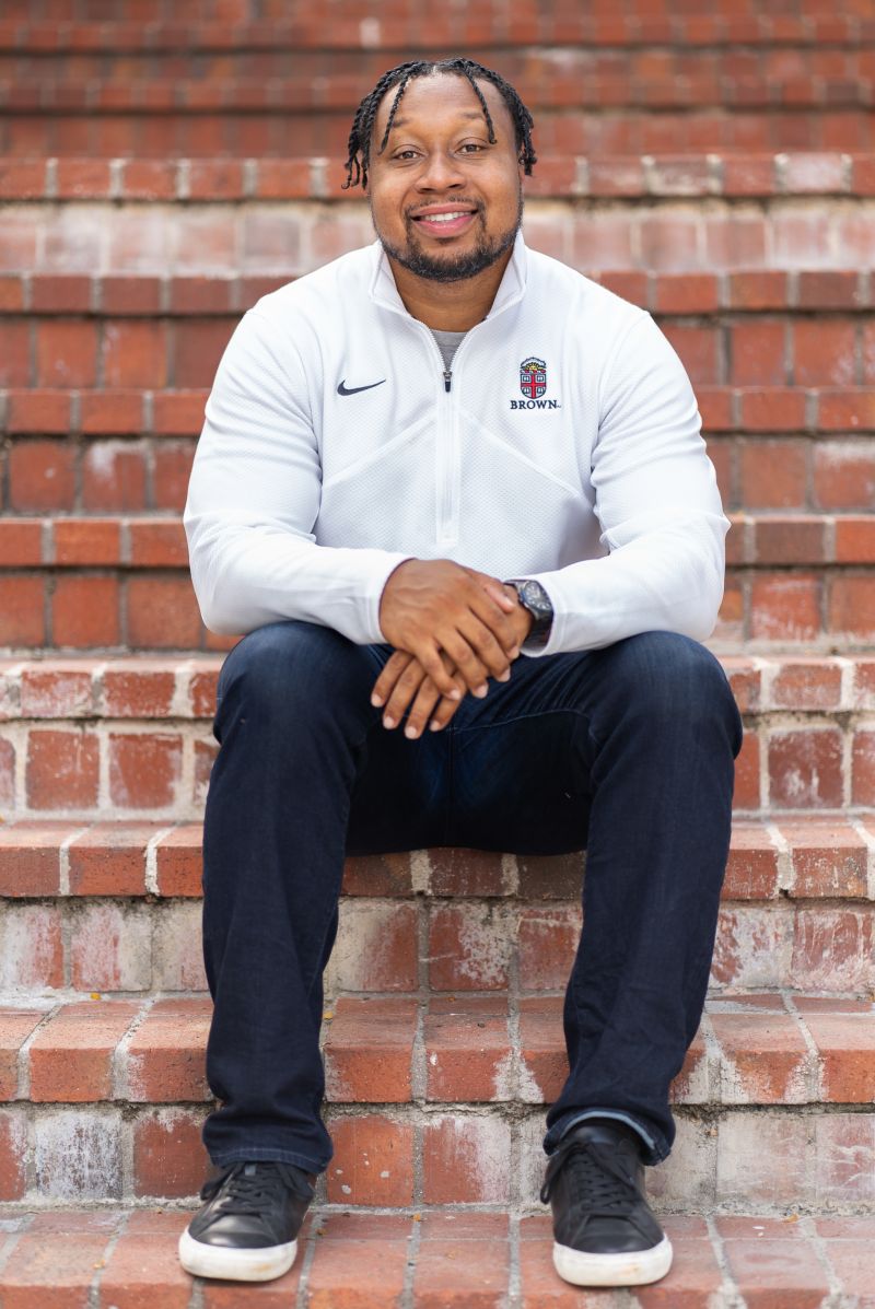 Shawn Gregoire, Founder and CEO of Capstone Tech, seated on brick steps wearing a Brown University pullover
